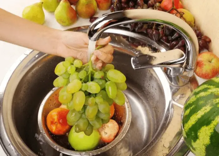 grapes and other fruits being washed in the sink