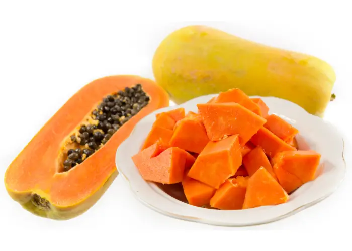 papaya cut in half and many pieces in a plate on a white background