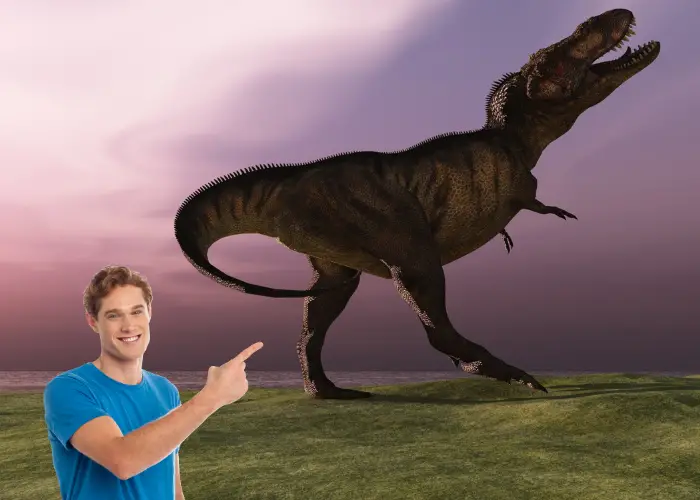 a man in blue shirt pointing to a T-rex dinosaur
